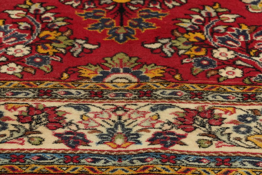 A hand-knotted Sarough rug from the Middle East featuring a vibrant red field and intricate floral patterns.
