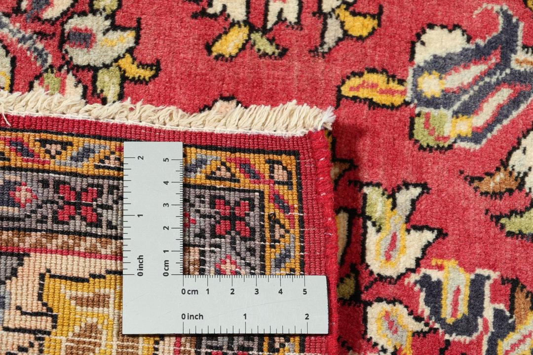 A hand-knotted Sarough rug from the Middle East featuring a vibrant red field and intricate floral patterns.