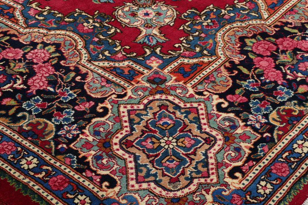 A hand-knotted Mashad rug from the Middle East in dark-red and blue tones.