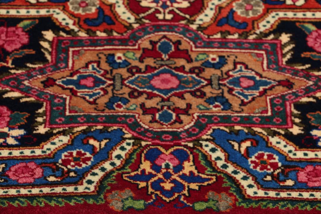 A hand-knotted Mashad rug from the Middle East in dark-red and blue tones.