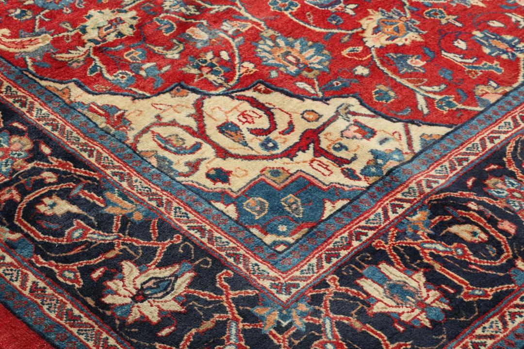 Een handgeknoopt rood Mahal-tapijt met een bloemenmedaillon en een marineblauwe rand.