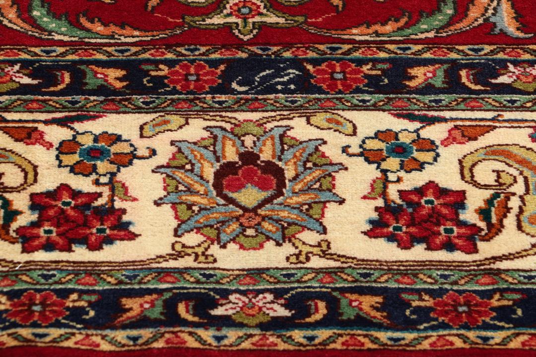 Een handgeknoopt tapijt uit het Midden-Oosten met een levendig rood veld en een ingewikkeld bloempatroon.