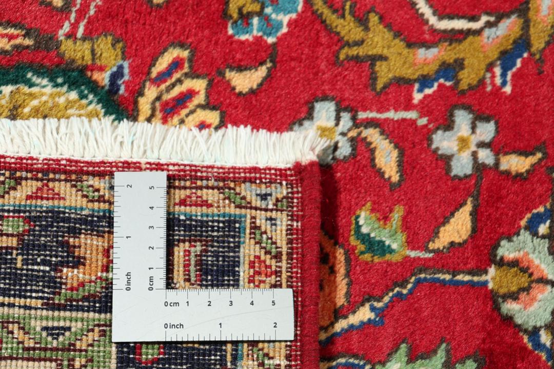 Een handgeknoopt tapijt uit het Midden-Oosten met een levendig rood veld en een ingewikkeld bloempatroon.