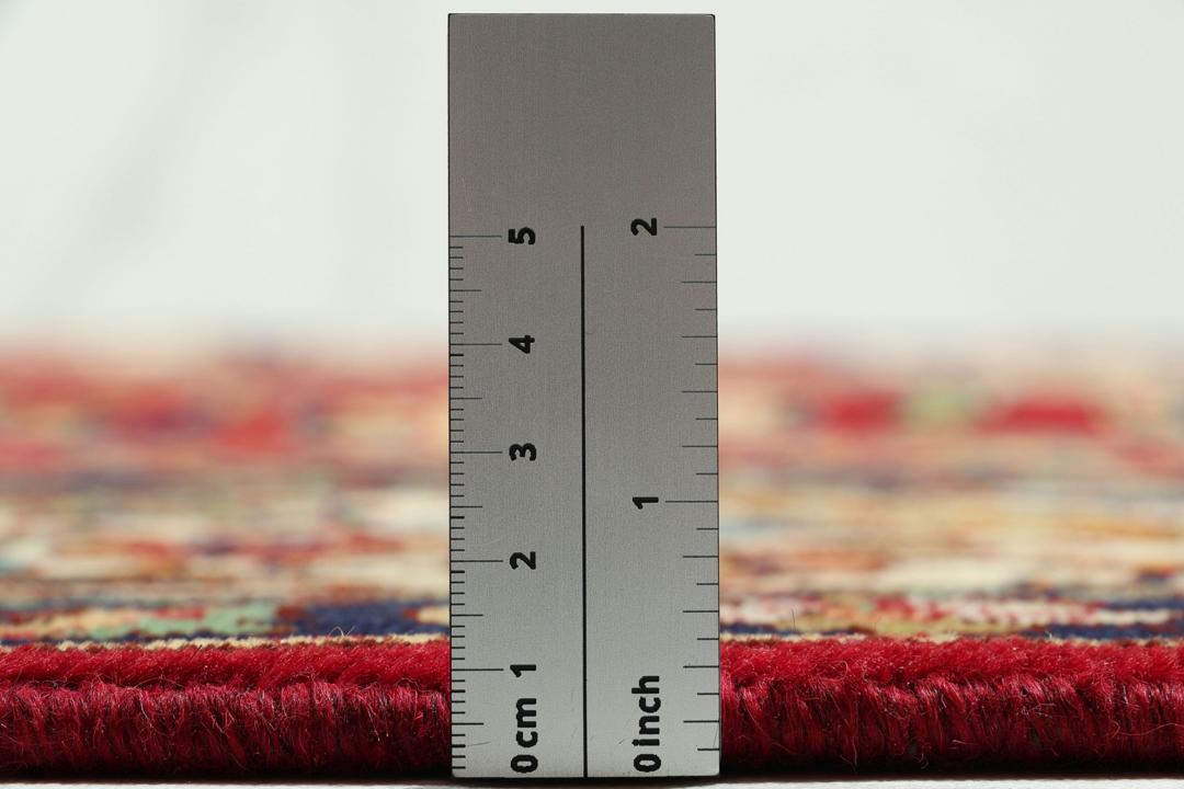 Een handgeknoopt tapijt uit het Midden-Oosten met een levendig rood veld en een ingewikkeld bloempatroon.