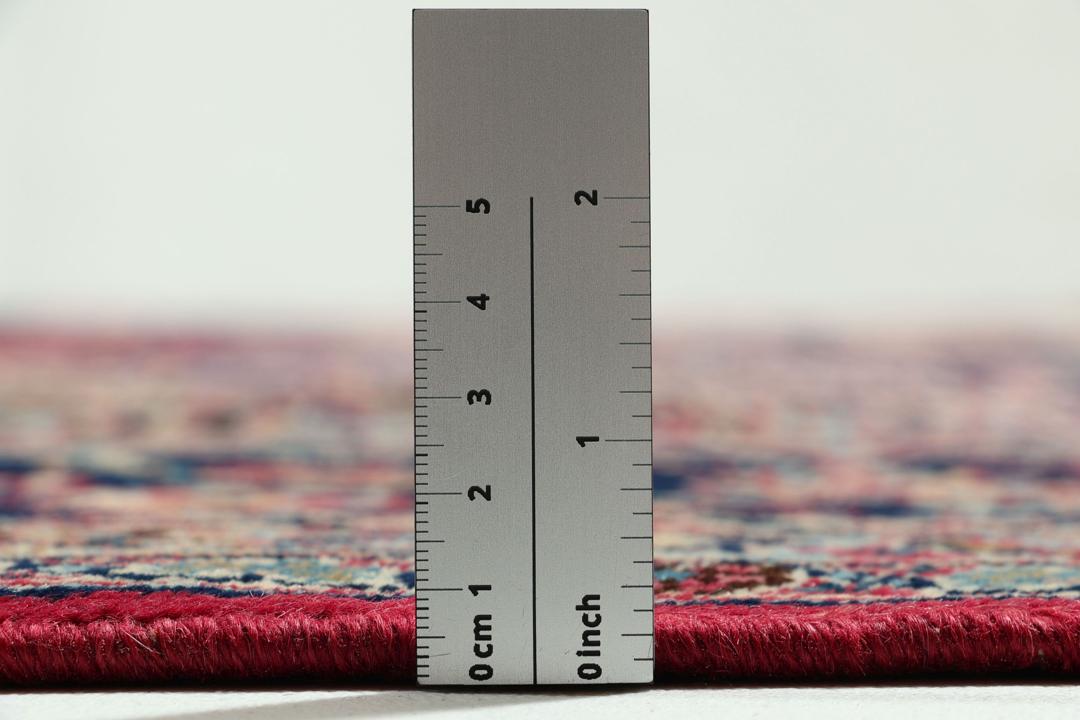Un tapis Mashad noué main en provenance du Moyen-Orient avec un champ rouge et un motif de médaillon traditionnel.
