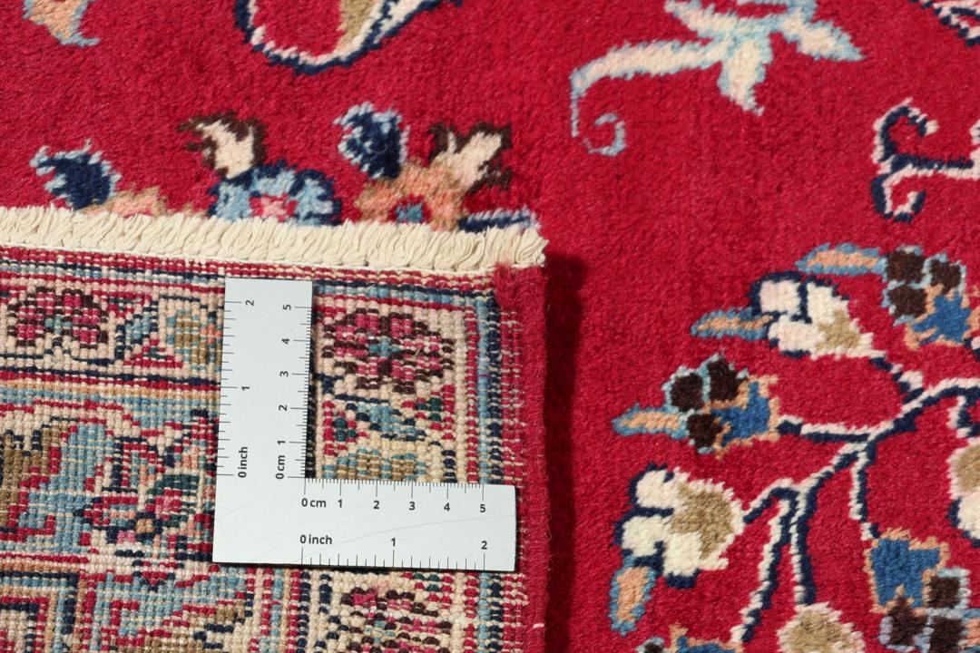 Un tapis Mashad noué main en provenance du Moyen-Orient avec un champ rouge et un motif de médaillon traditionnel.