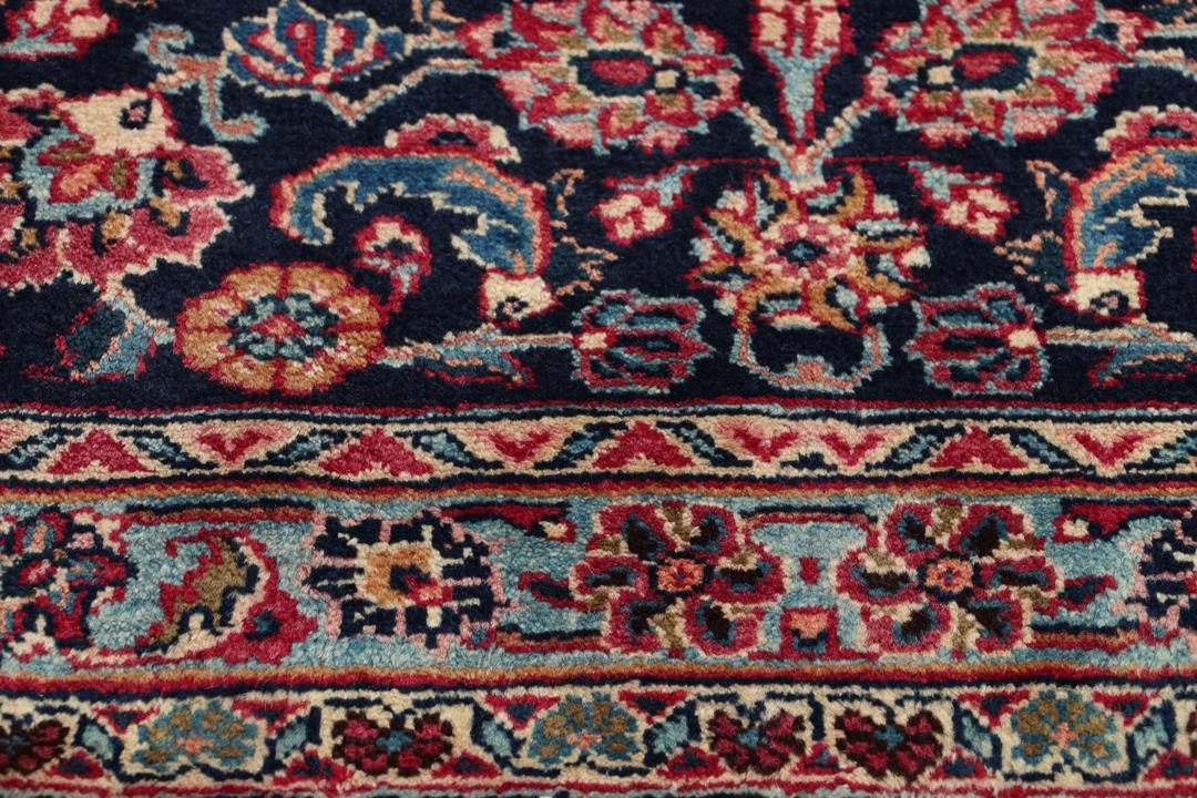 Un tapis Mashad noué main en provenance du Moyen-Orient avec un champ rouge et un motif de médaillon traditionnel.