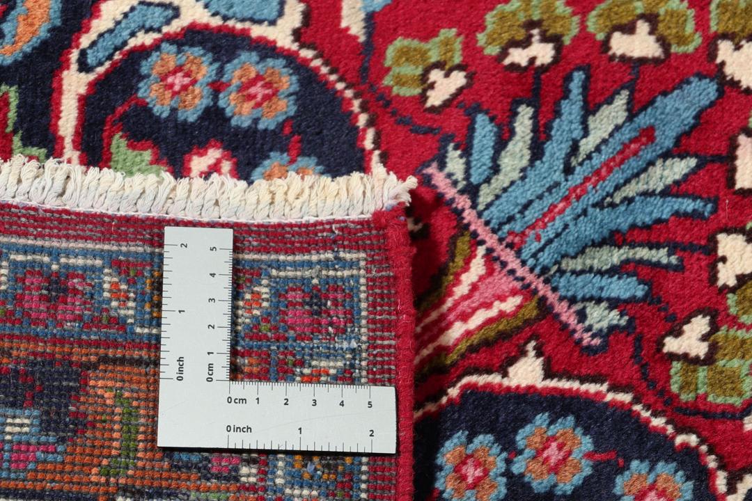 Et håndknyttet Mashad-tæppe fra Mellemøsten med en rød bund og traditionelle blomstermotiver.