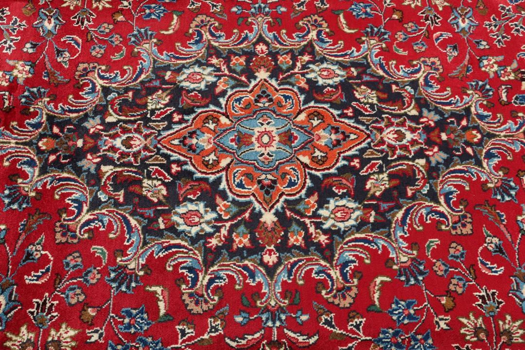 A hand-knotted Mashad rug from the Middle East in deep red and navy tones.