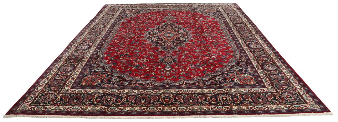 A hand-knotted Mashad rug from the Middle East in deep red and navy tones.