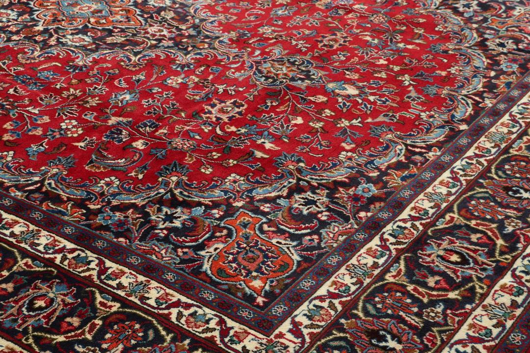 A hand-knotted Mashad rug from the Middle East in deep red and navy tones.