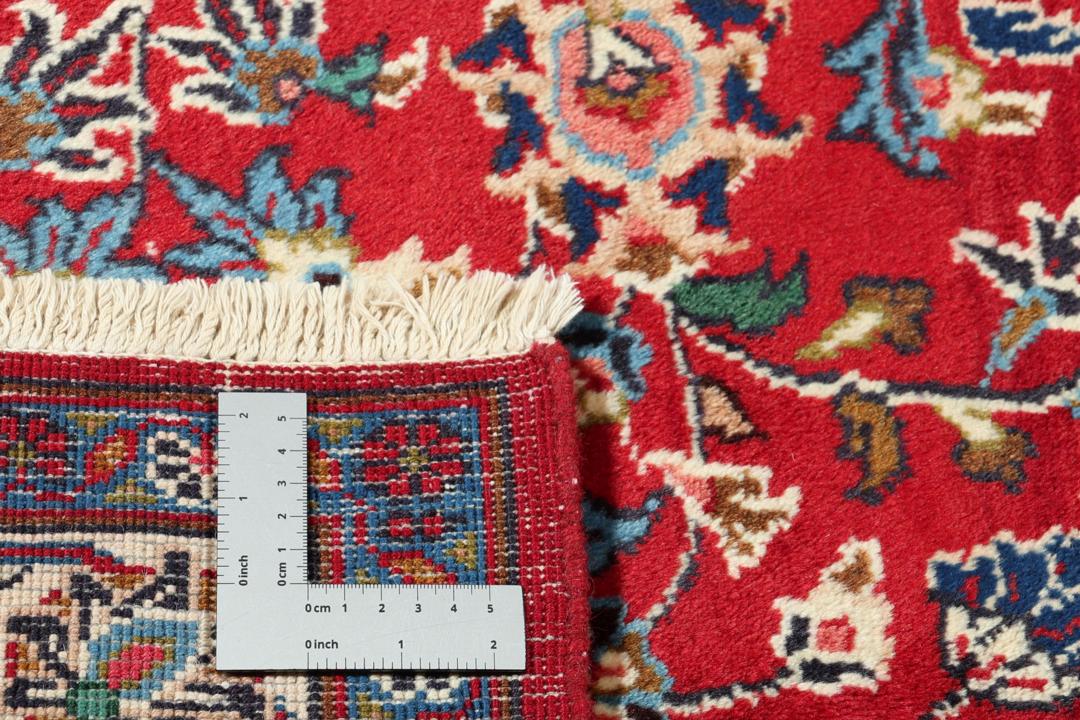 A hand-knotted Mashad rug from the Middle East in deep red and navy tones.