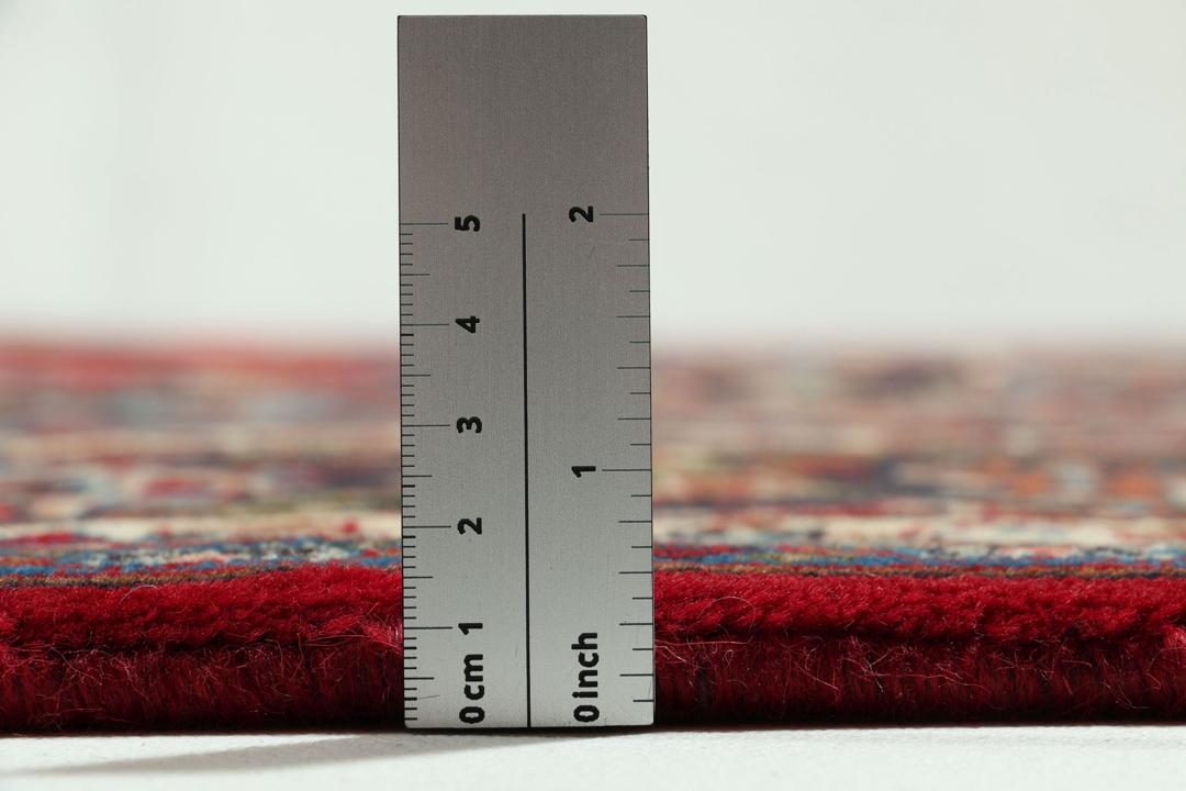 A hand-knotted Mashad rug from the Middle East in deep red and navy tones.