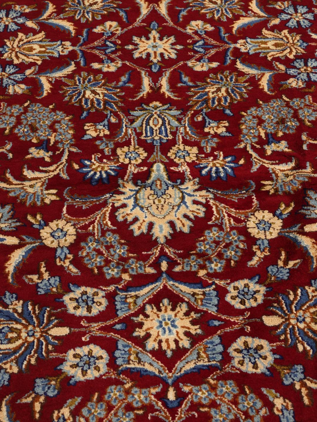 A hand-knotted Kerman rug from the Middle East featuring a vibrant red field and intricate floral patterns.