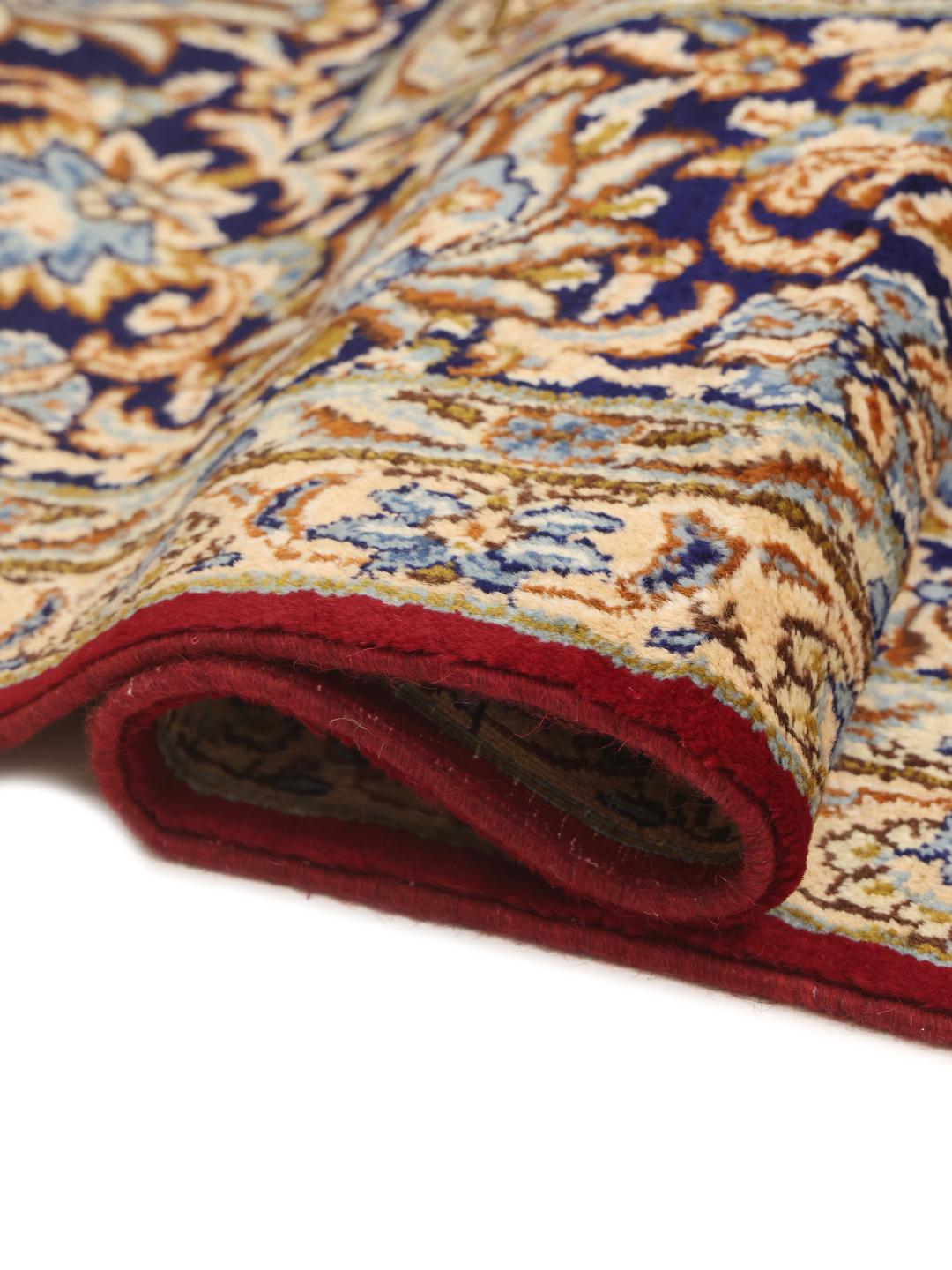 A hand-knotted Kerman rug from the Middle East featuring a vibrant red field and intricate floral patterns.
