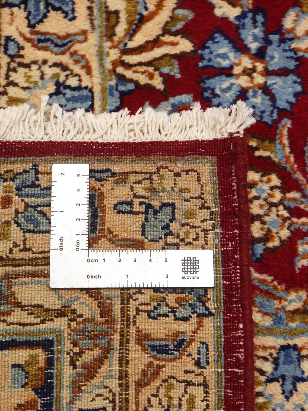 A hand-knotted Kerman rug from the Middle East featuring a vibrant red field and intricate floral patterns.