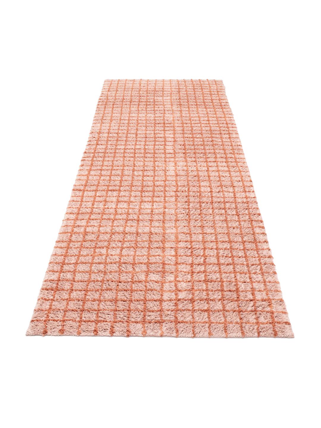 Een roze en terracotta gekleurde loper met een ruitpatroon
