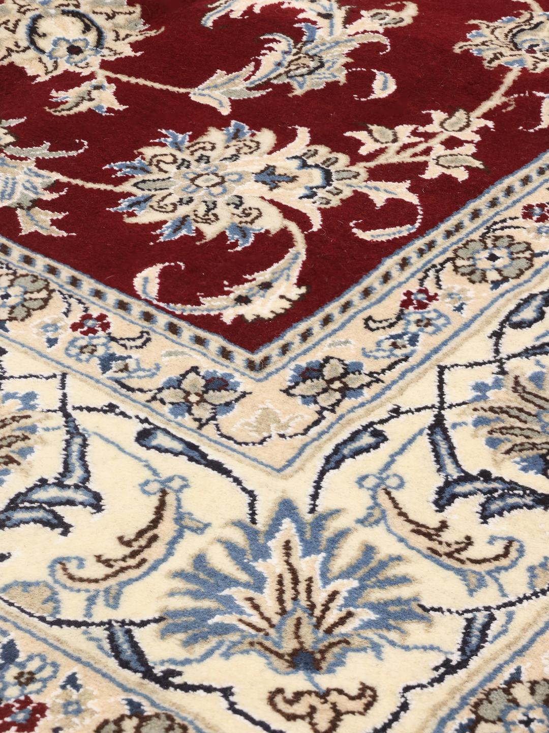 Hand-knotted Nain rug from the Middle East featuring a dark-red floral field and blue border
