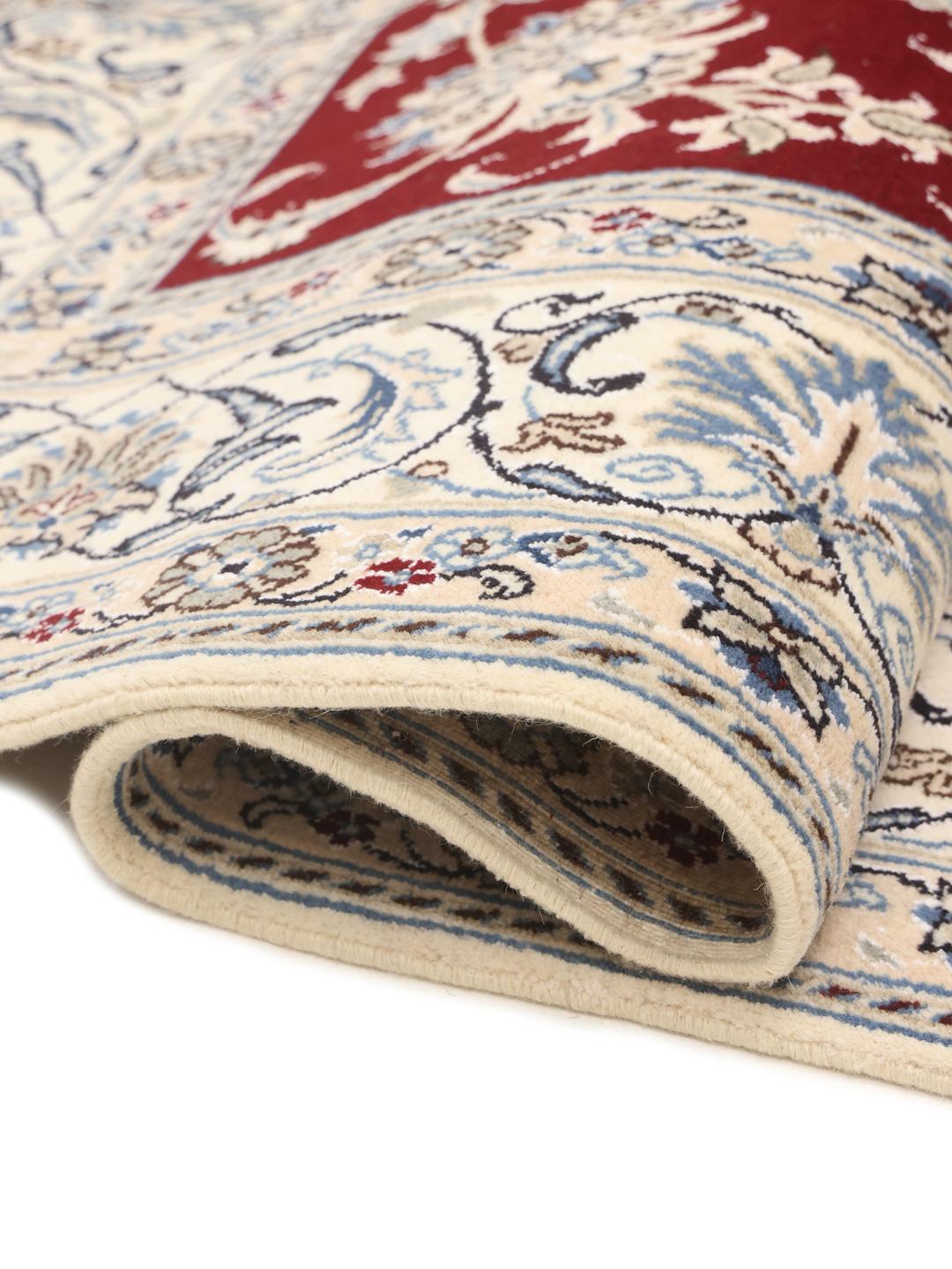 Hand-knotted Nain rug from the Middle East featuring a dark-red floral field and blue border