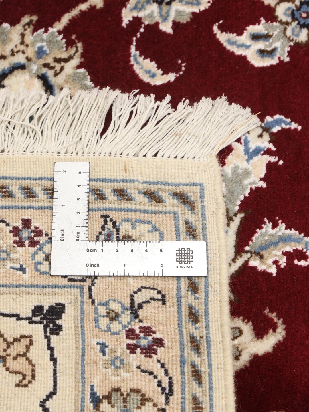 Hand-knotted Nain rug from the Middle East featuring a dark-red floral field and blue border
