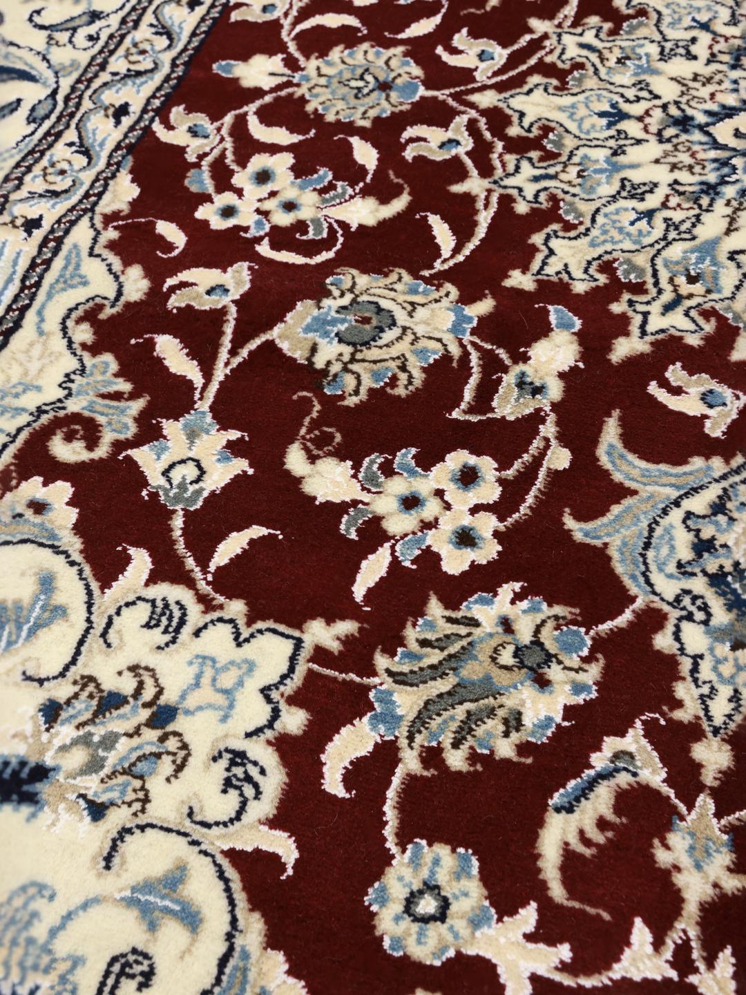 Hand-knotted Nain rug from the Middle East featuring a dark-red and blue floral medallion design.