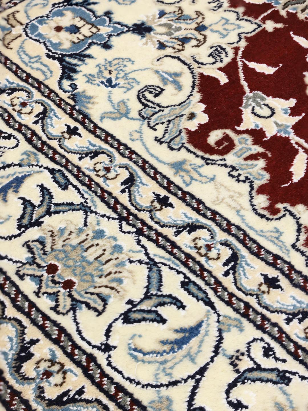 Hand-knotted Nain rug from the Middle East featuring a dark-red and blue floral medallion design.