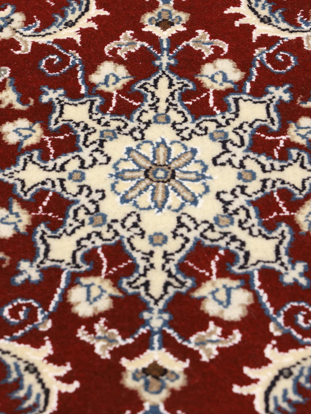 Hand-knotted Nain rug from the Middle East in dark-red with floral motifs.