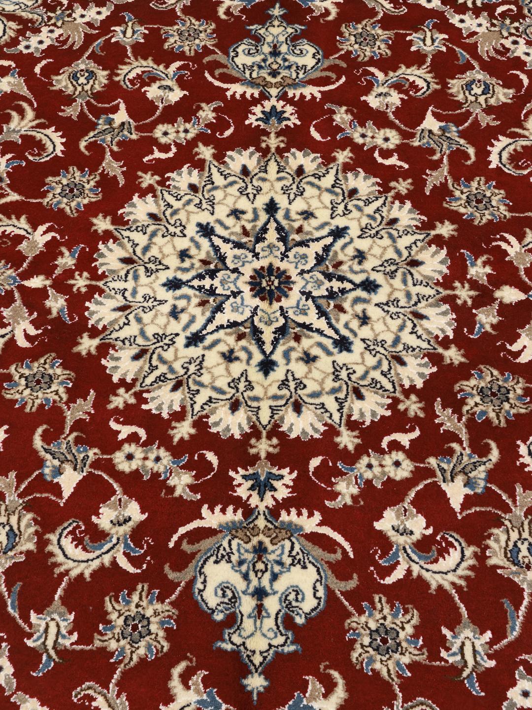 Hand-knotted Nain rug from the Middle East with a red field and floral medallion pattern.