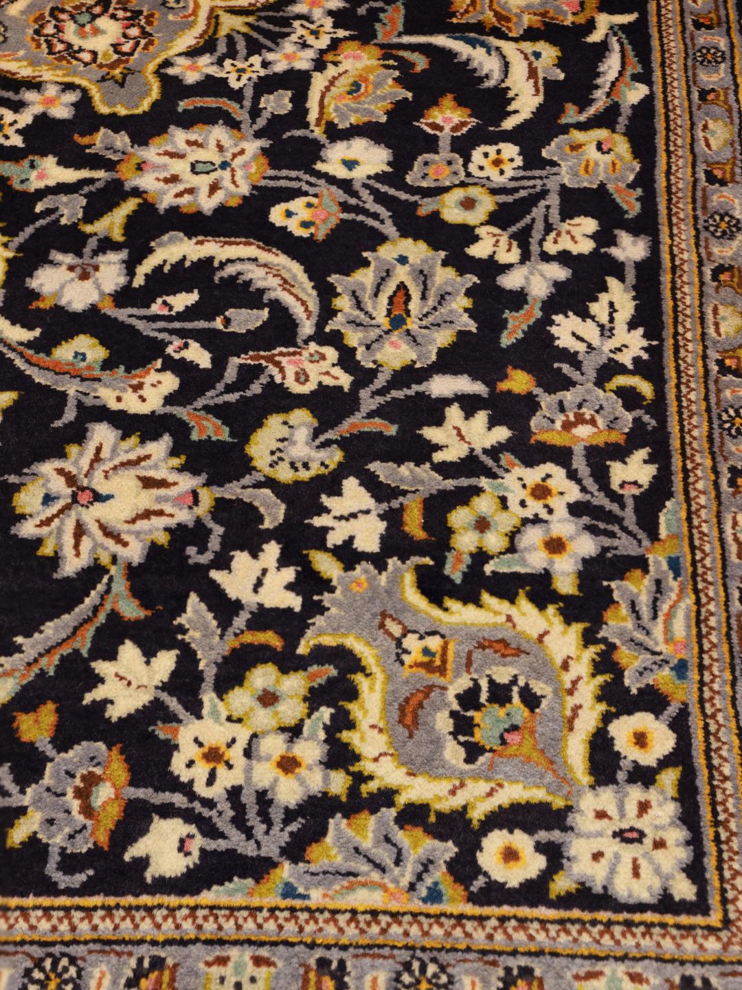 Een handgeknoopt Keshan-tapijt uit het Midden-Oosten in donkerblauw met bloemmotieven.
