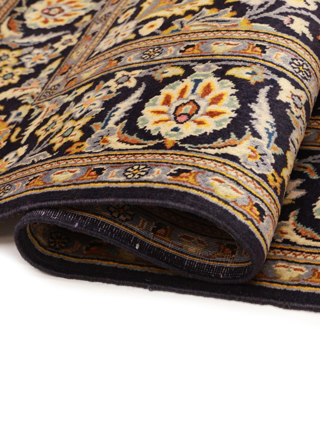 Een handgeknoopt Keshan-tapijt uit het Midden-Oosten in donkerblauw met bloemmotieven.