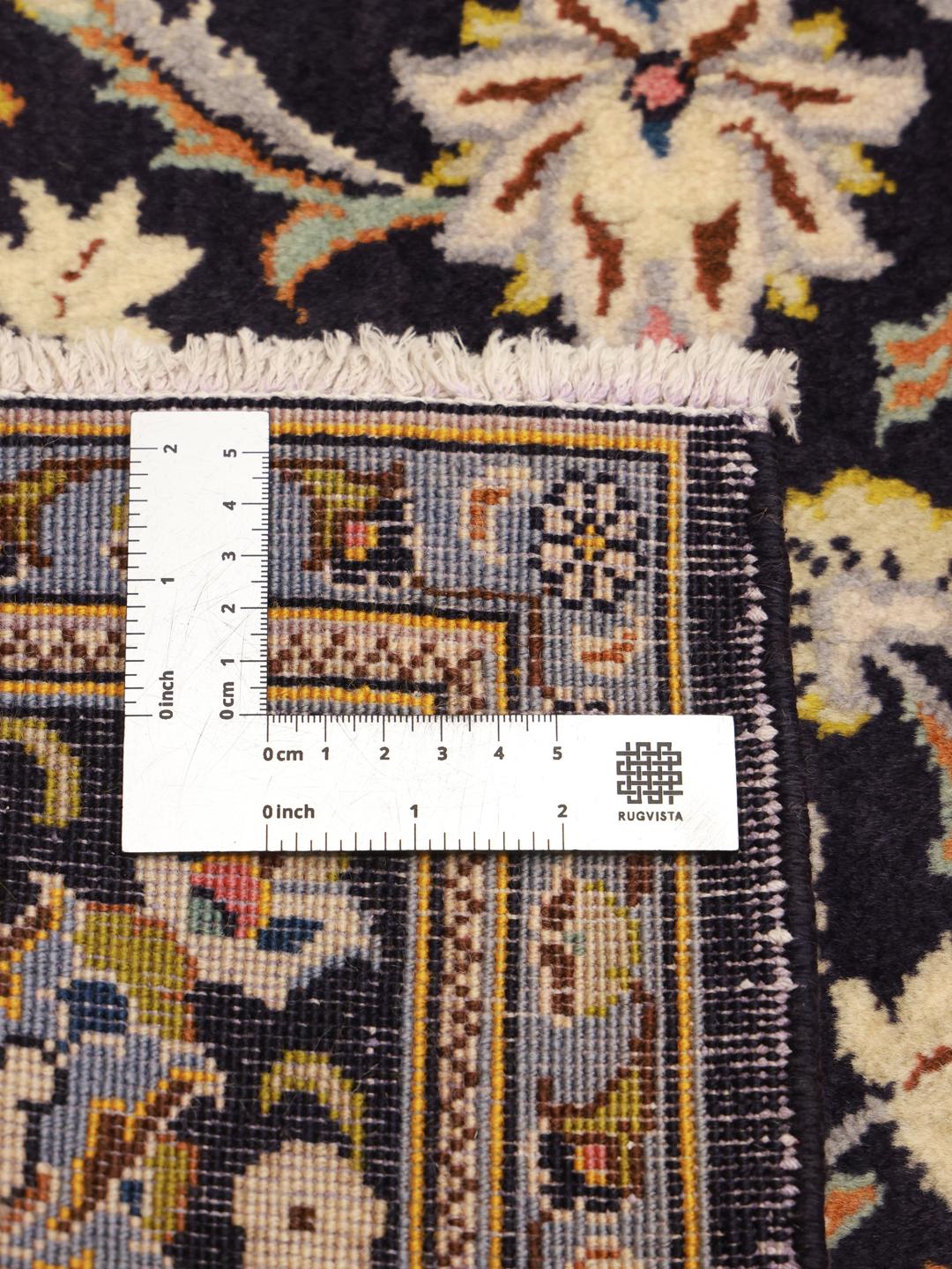 Een handgeknoopt Keshan-tapijt uit het Midden-Oosten in donkerblauw met bloemmotieven.