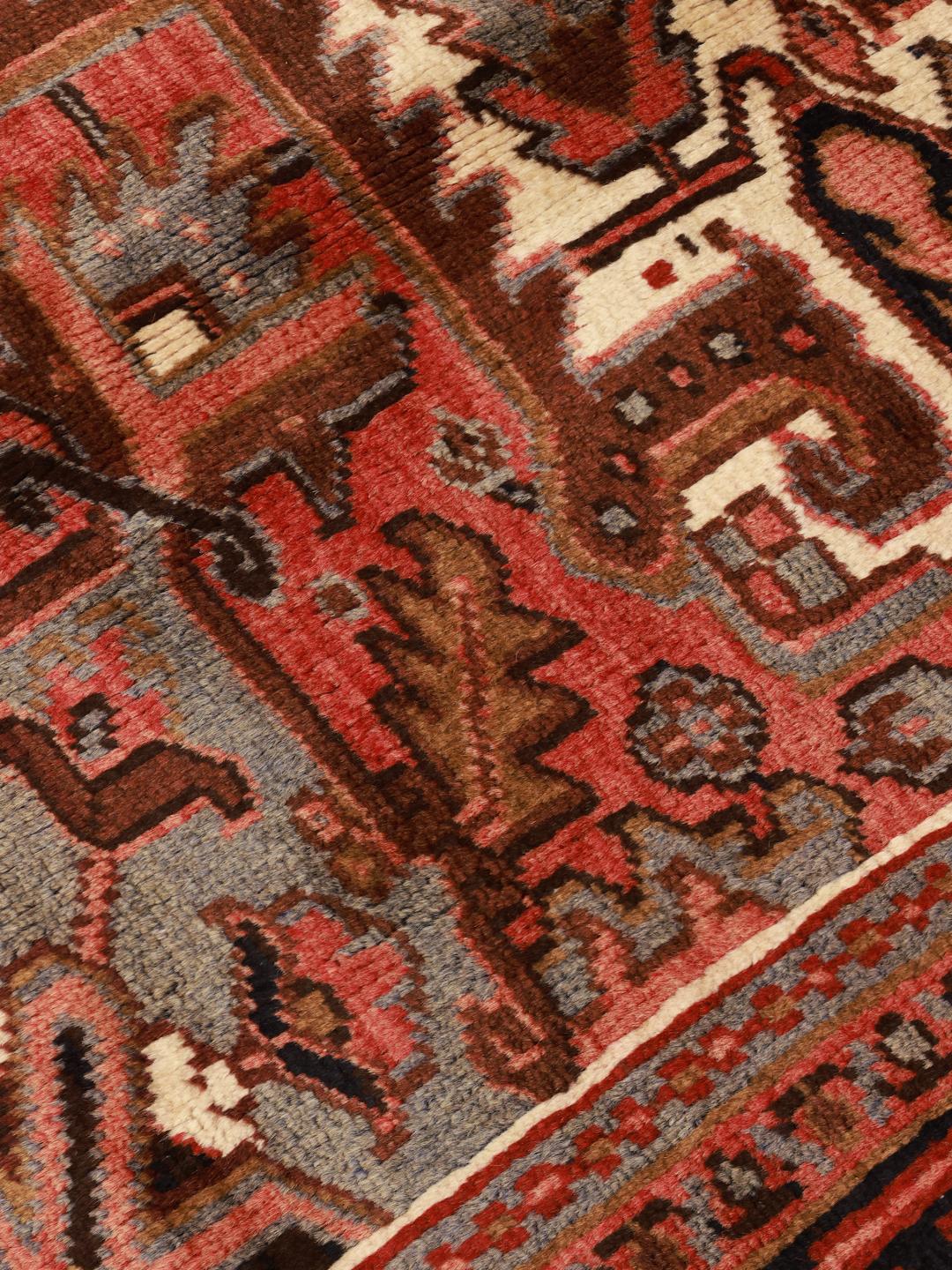 A hand-knotted Heriz rug from the Middle East with a striking red field and intricate geometric medallion.