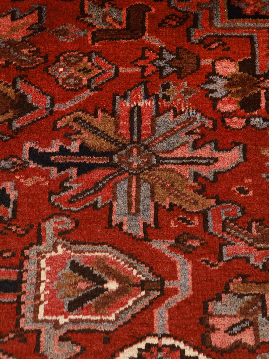 A hand-knotted Heriz rug from the Middle East with a striking red field and intricate geometric medallion.