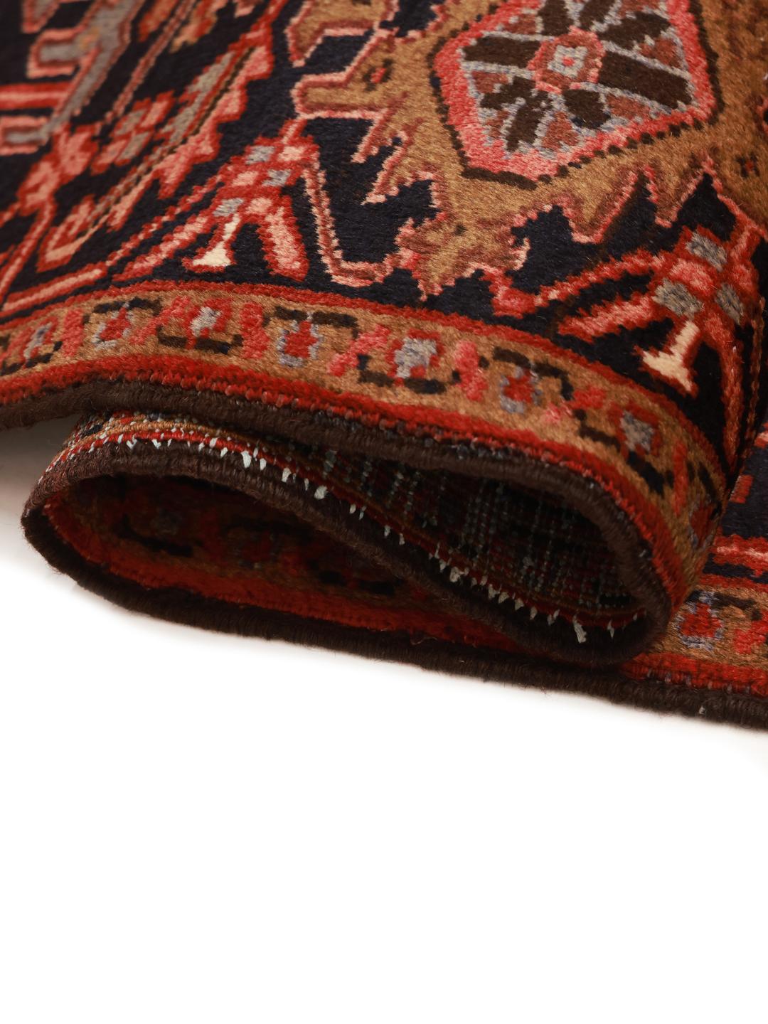 A hand-knotted Heriz rug from the Middle East with a striking red field and intricate geometric medallion.