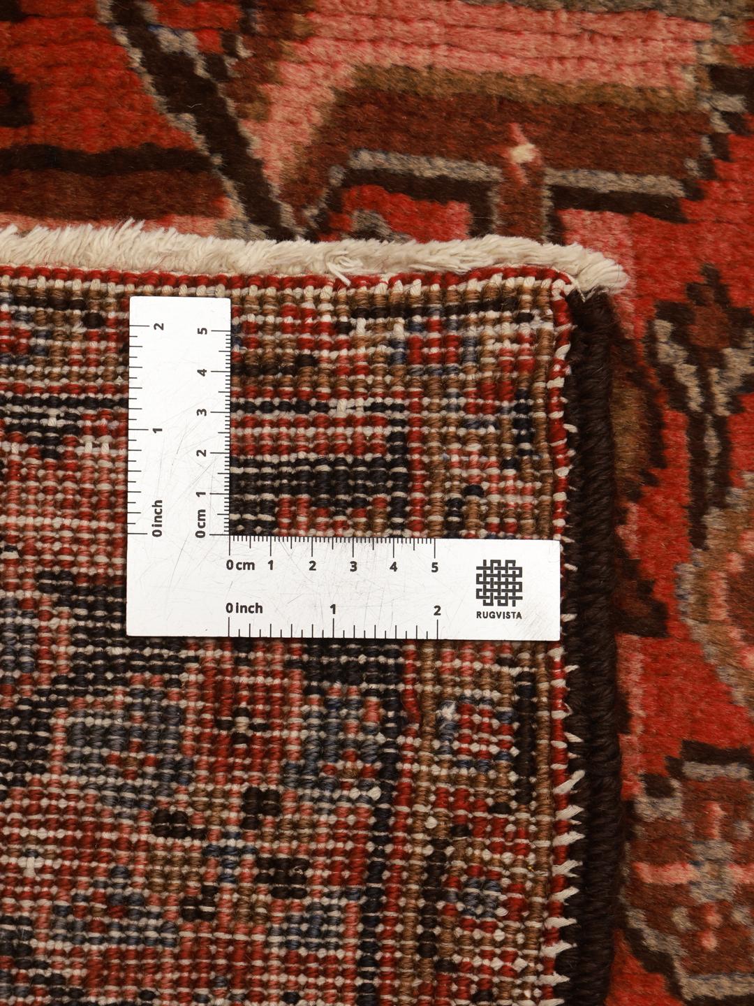 A hand-knotted Heriz rug from the Middle East with a striking red field and intricate geometric medallion.