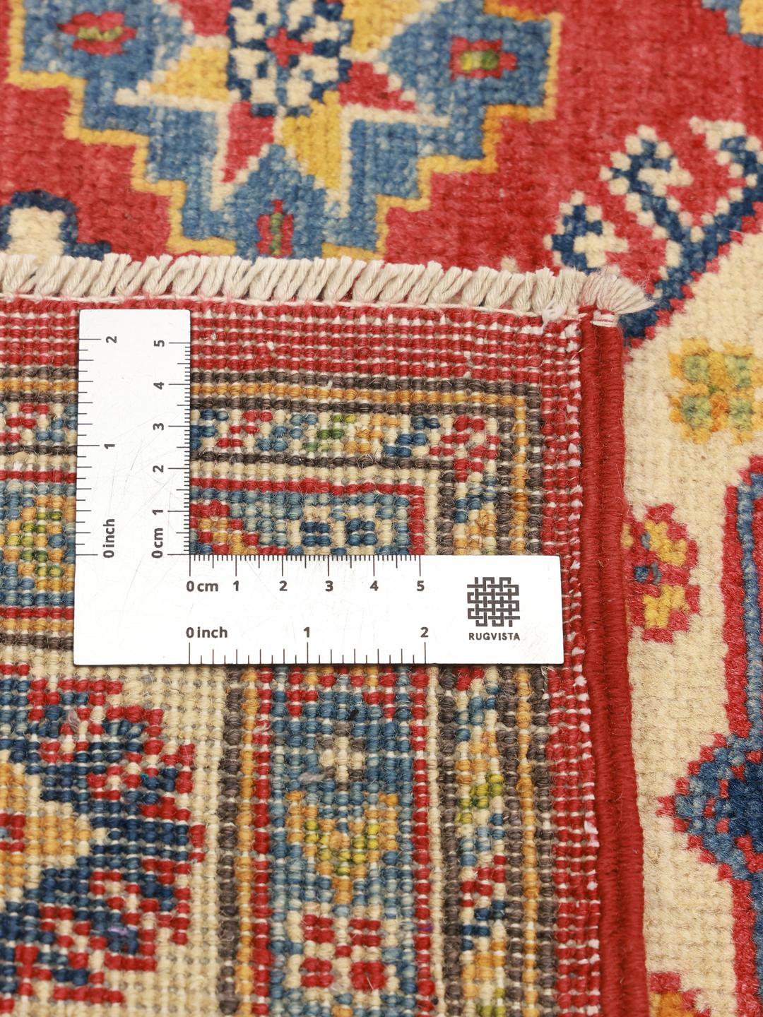 Covor afgan Kazak înnodat manual cu modele geometrice în nuanțe de roșu, albastru și galben.