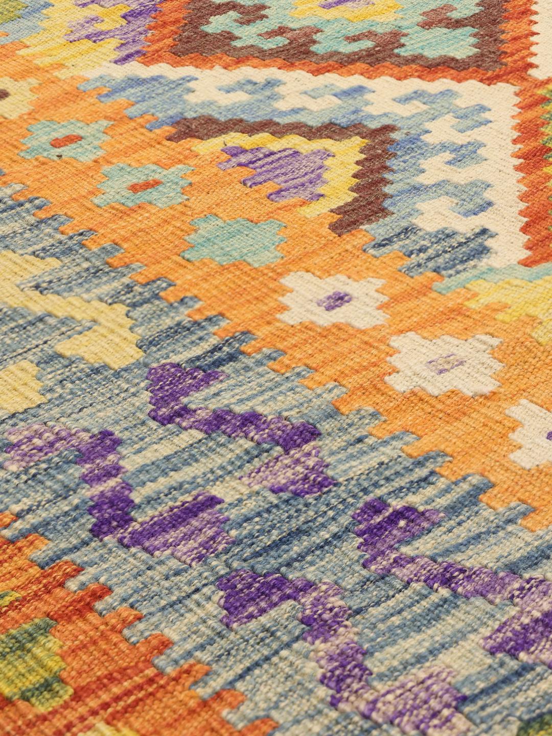 A large, rectangular hand-woven Afghan Kelim rug featuring a vibrant, multi-coloured diamond pattern.