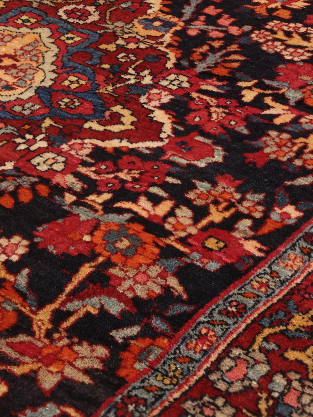 A hand-knotted Hamadan rug from the Middle East with a dark-red and black floral design.