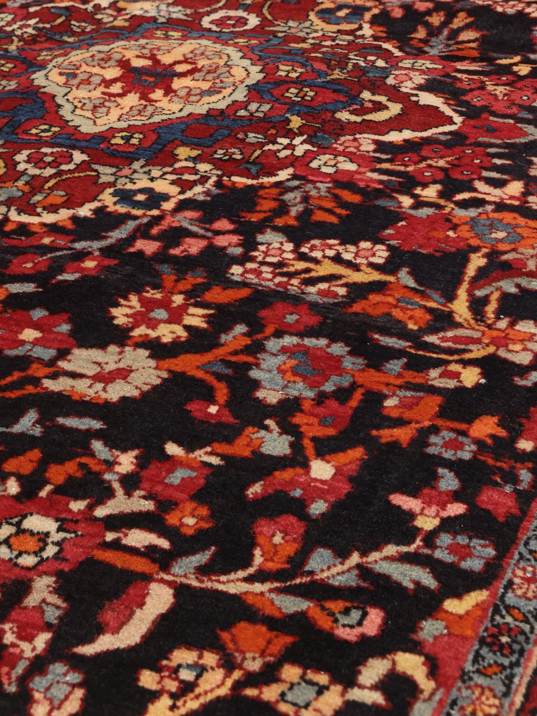 A hand-knotted Hamadan rug from the Middle East with a dark-blue and red floral design.