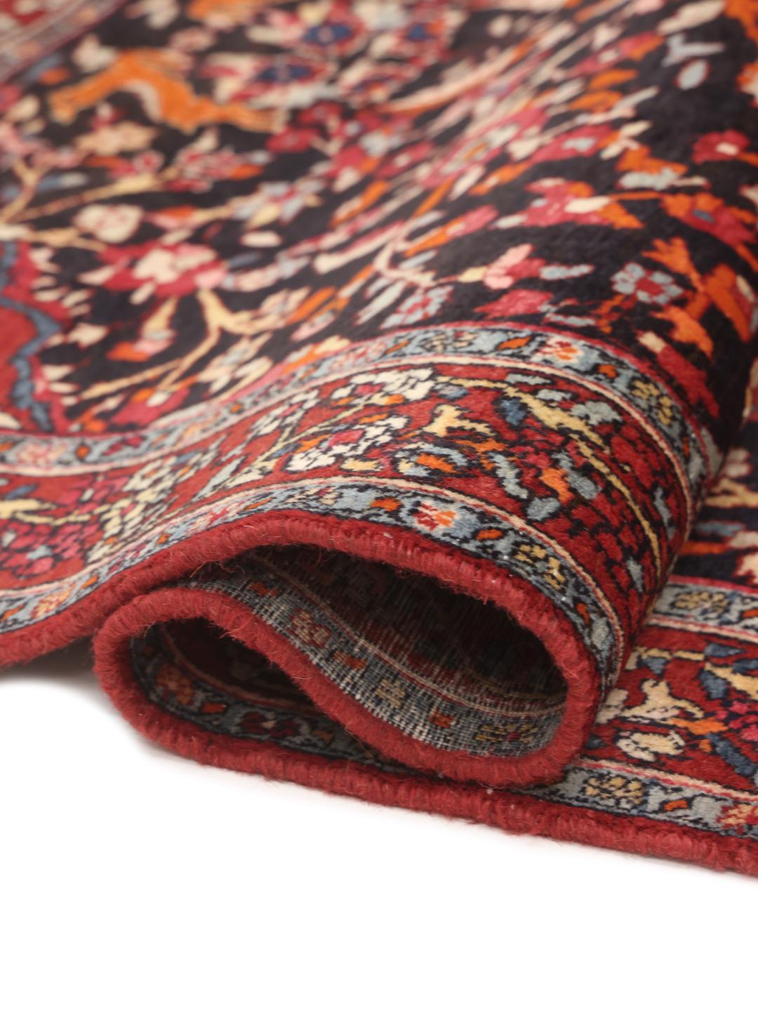 A hand-knotted Hamadan rug from the Middle East with a dark-blue and red floral design.
