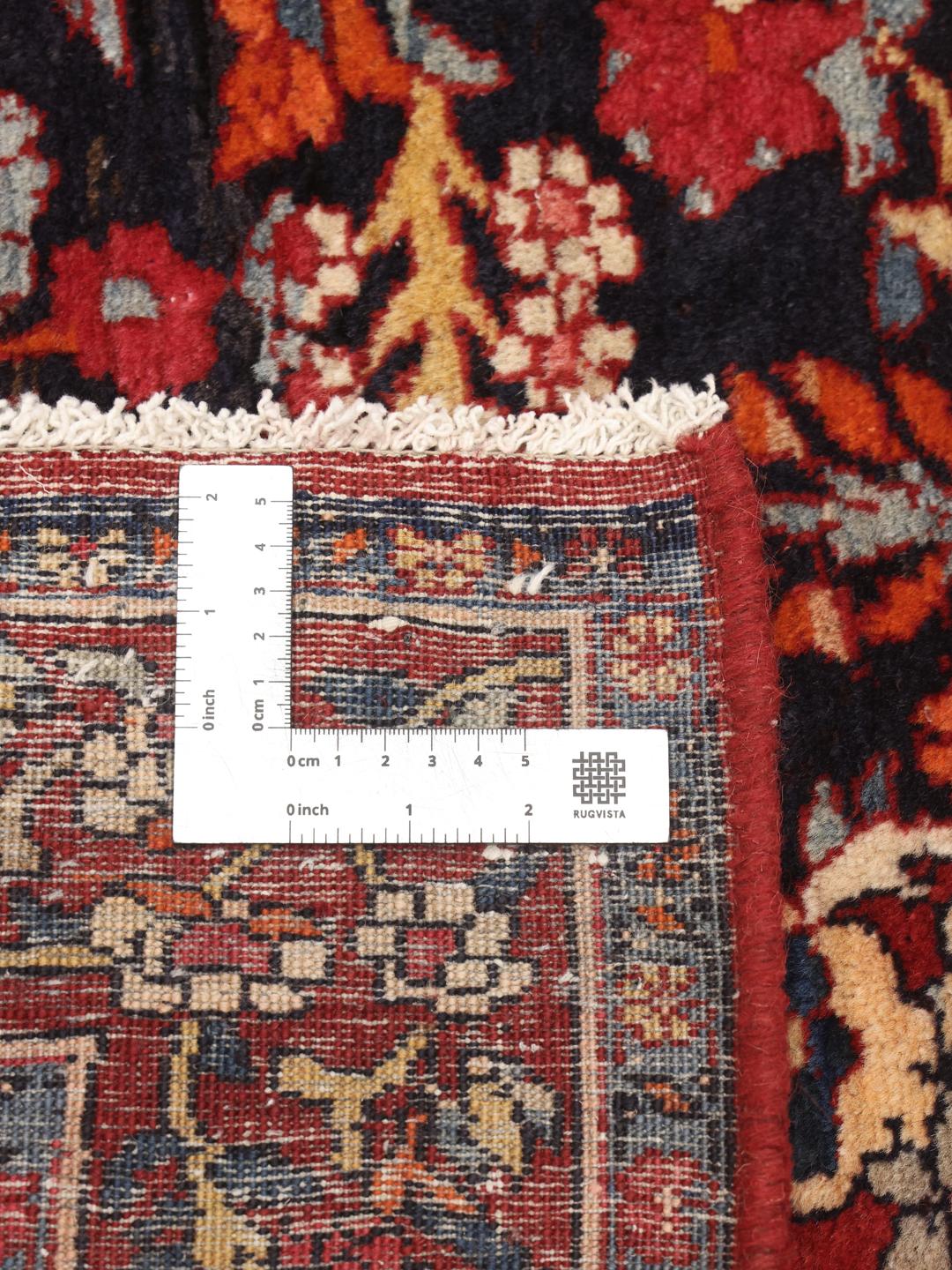 A hand-knotted Hamadan rug from the Middle East with a dark-blue and red floral design.