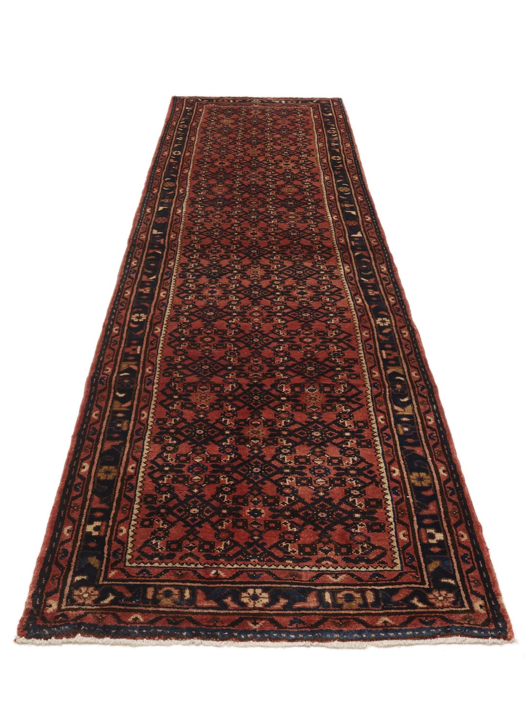 A hand-knotted Hosseinabad runner from the Middle East featuring a red and dark blue geometric pattern.