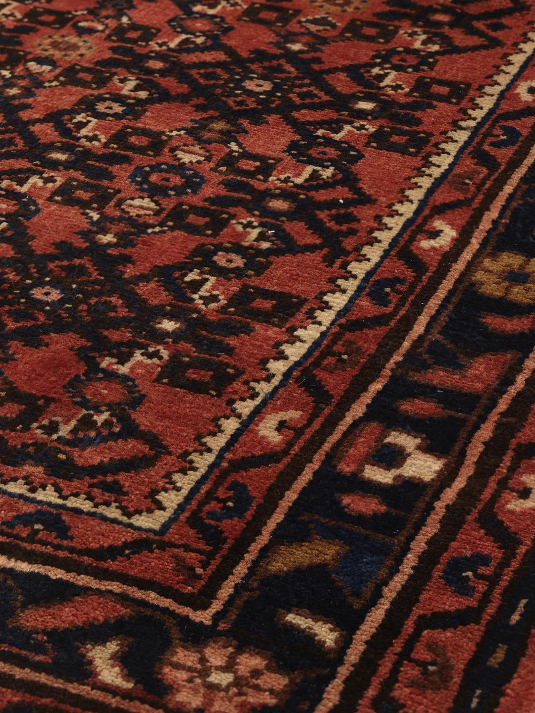 A hand-knotted Hosseinabad runner from the Middle East featuring a red and dark blue geometric pattern.