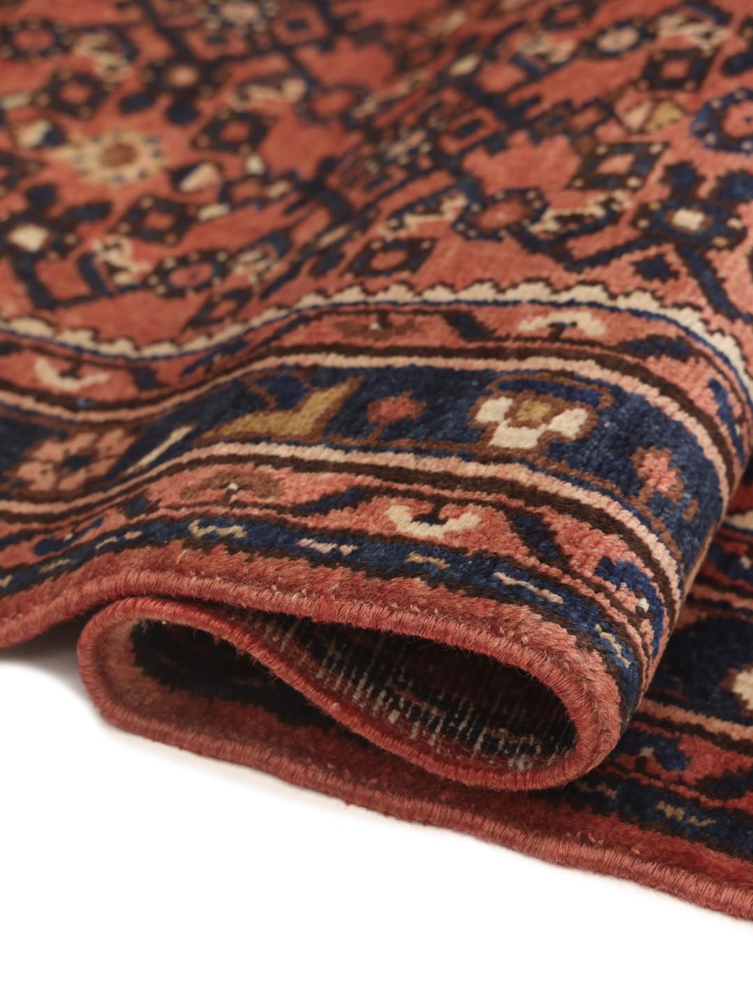 A hand-knotted Hosseinabad runner from the Middle East featuring a red and dark blue geometric pattern.