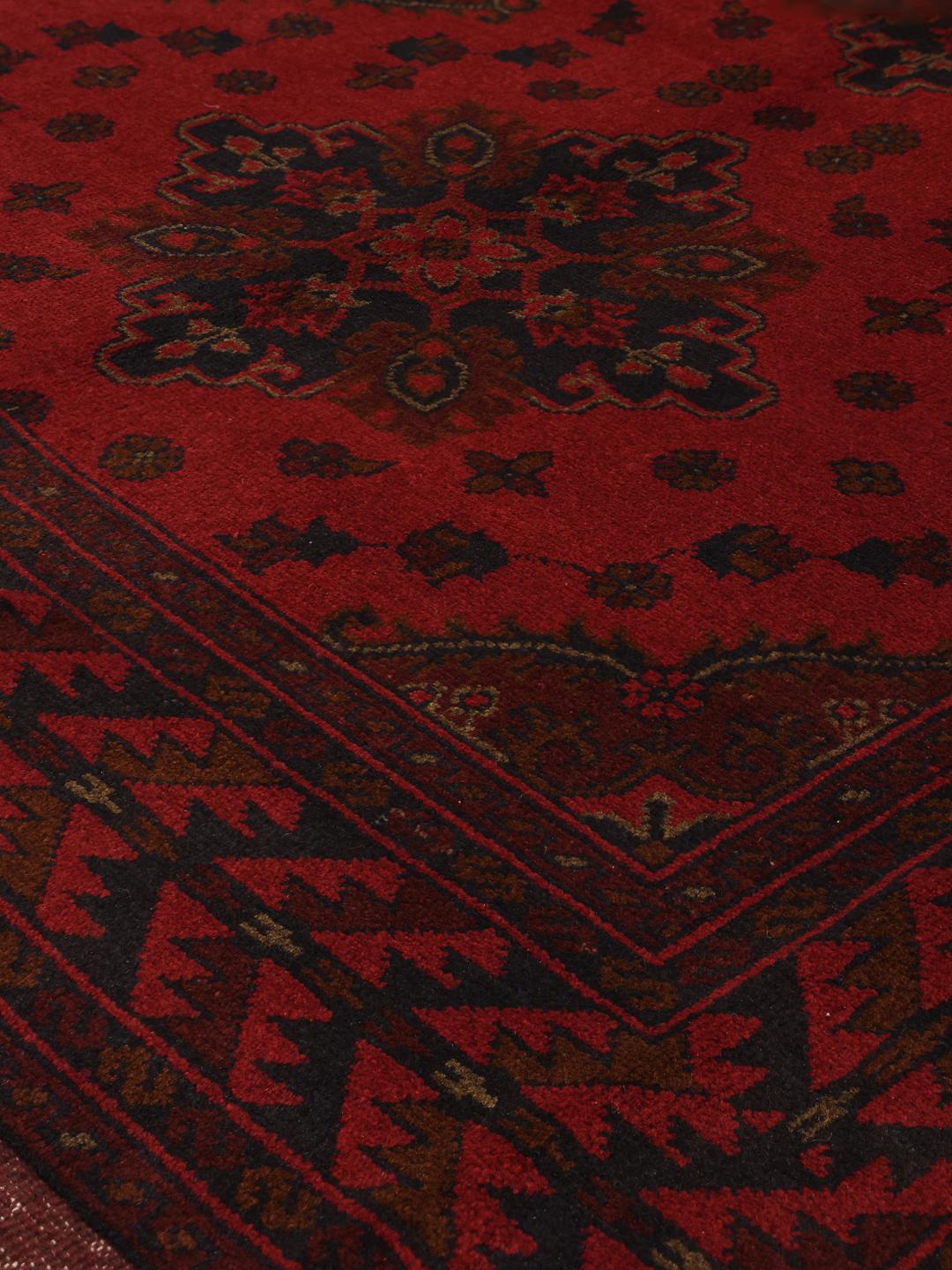 Tapis afghan noué à la main dans des tons rouge profond avec des motifs géométriques traditionnels