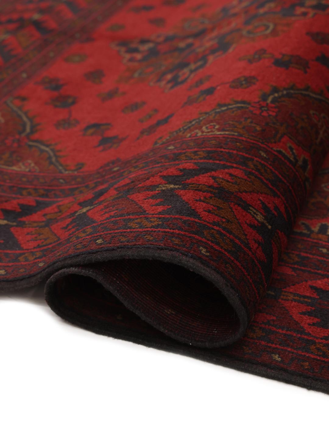 Tapis afghan noué à la main dans des tons rouge profond avec des motifs géométriques traditionnels
