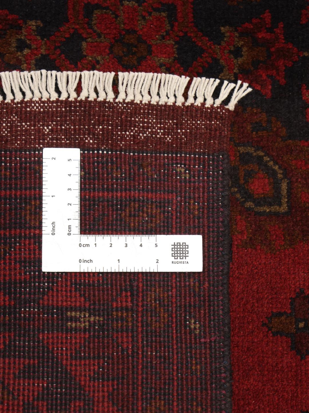 Tapis afghan noué à la main dans des tons rouge profond avec des motifs géométriques traditionnels