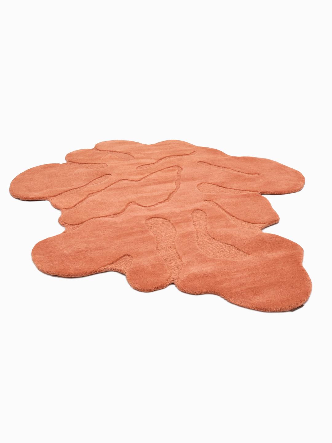 Handgemaakt oranje tapijt met een organische vorm en zachte wollen pool.