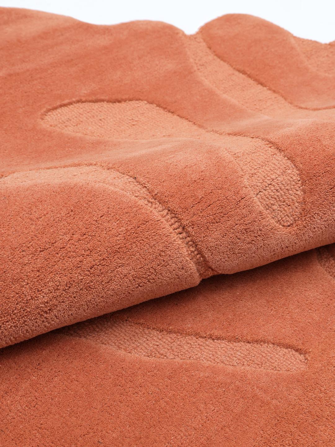 Handgemaakt oranje tapijt met een organische vorm en zachte wollen pool.