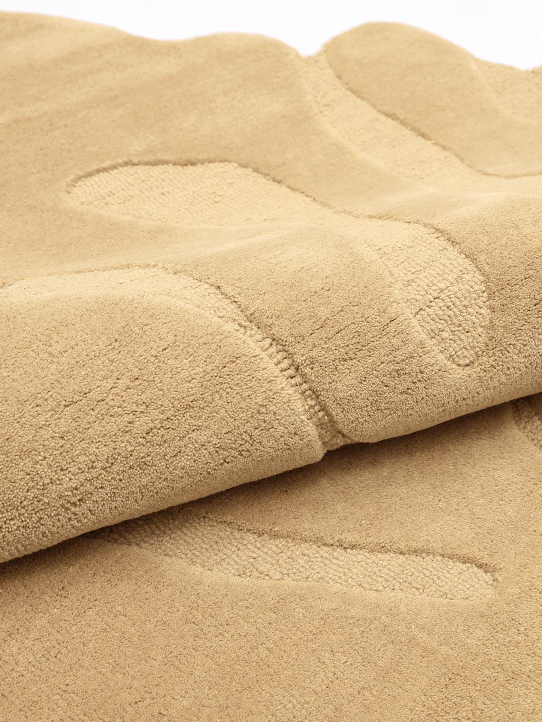 Uregelmæssigt formet beige tæppe